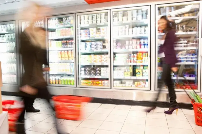 Customers walking in front of supermarket fridges